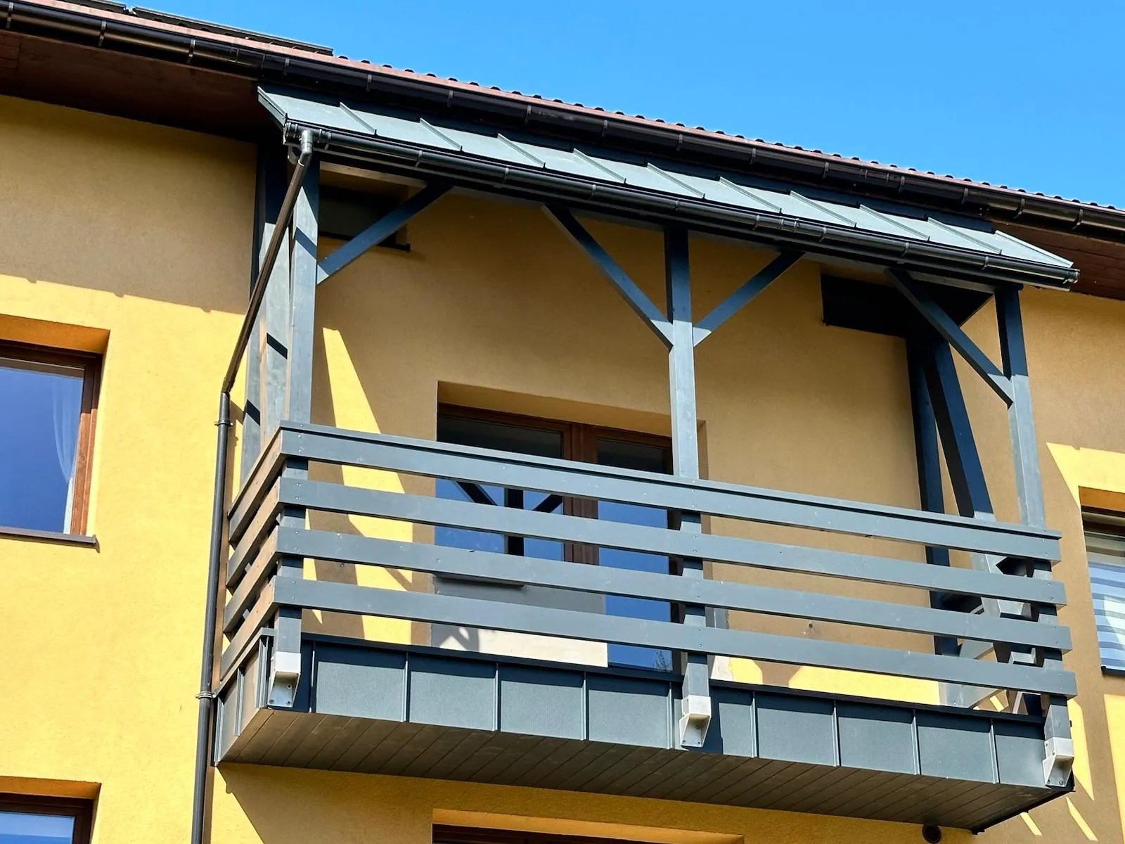 Gotowy drewniany balkon z zadaszeniem, dopasowany proporcjami do bryły domu.