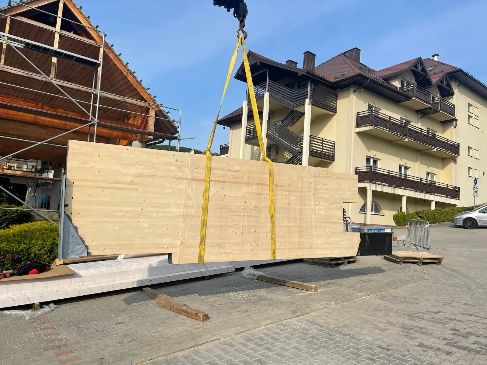 Montaż dużego elementu z drewna klejonego, kluczowego dla nowej konstrukcji wejścia.