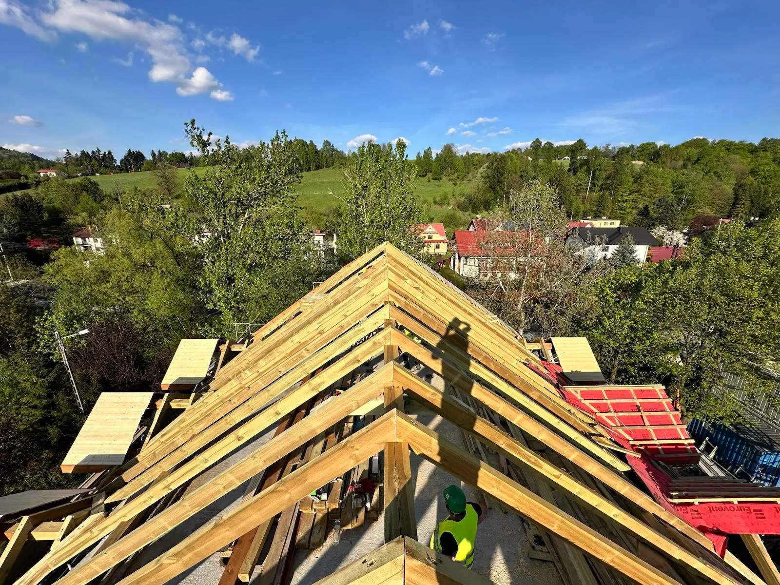 Widok z kalenicy pokazujący skalę więźby dachowej i postęp prac na całej połaci.