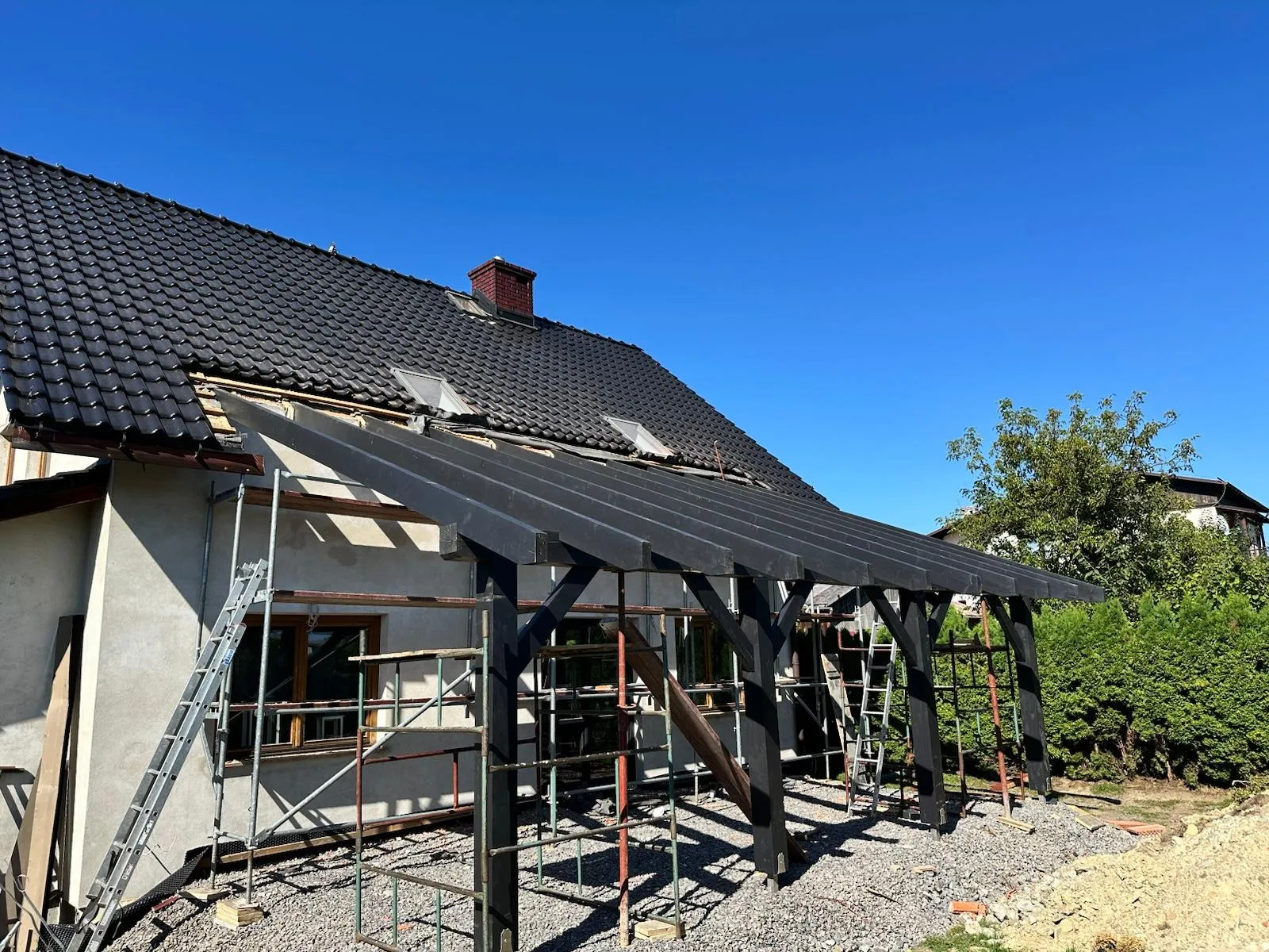 Zadaszenie wejścia przy domu, które porządkuje front budynku i osłania strefę wejściową.