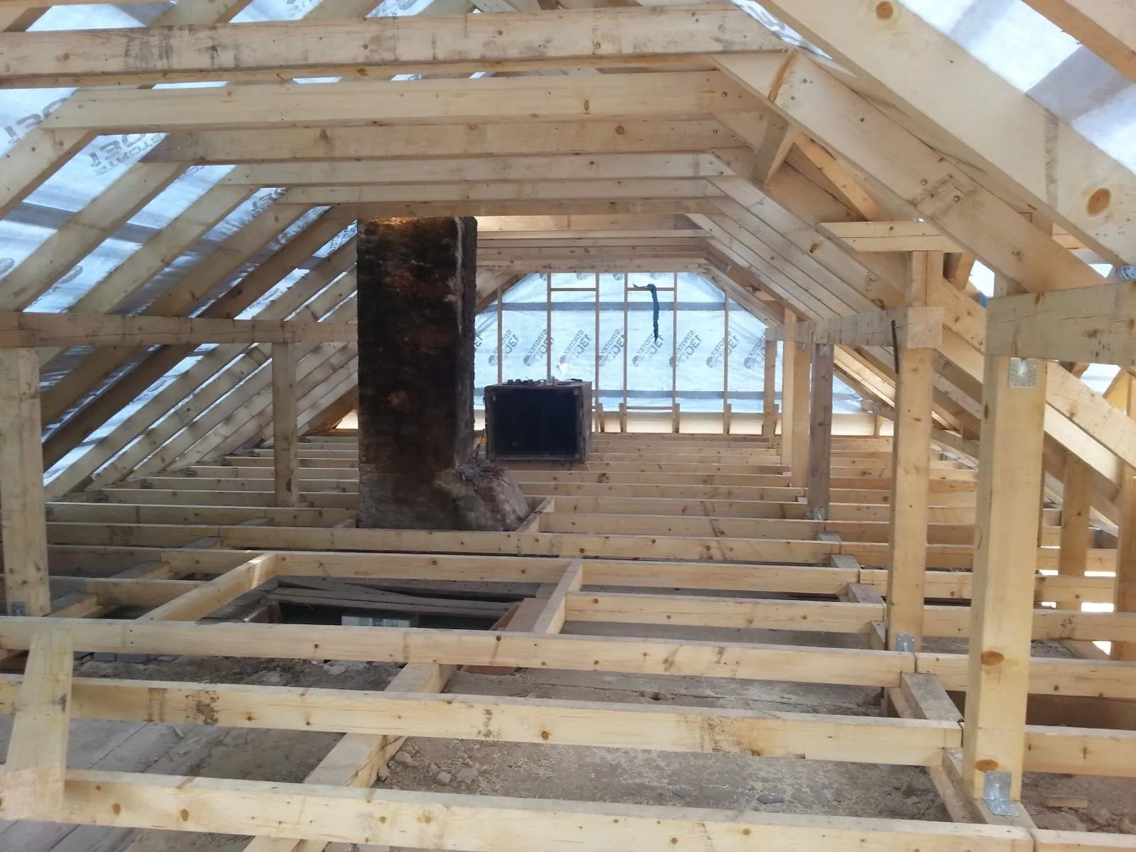 Wnętrze poddasza z czytelnym układem belek i precyzyjnie poprowadzoną konstrukcją wokół komina.