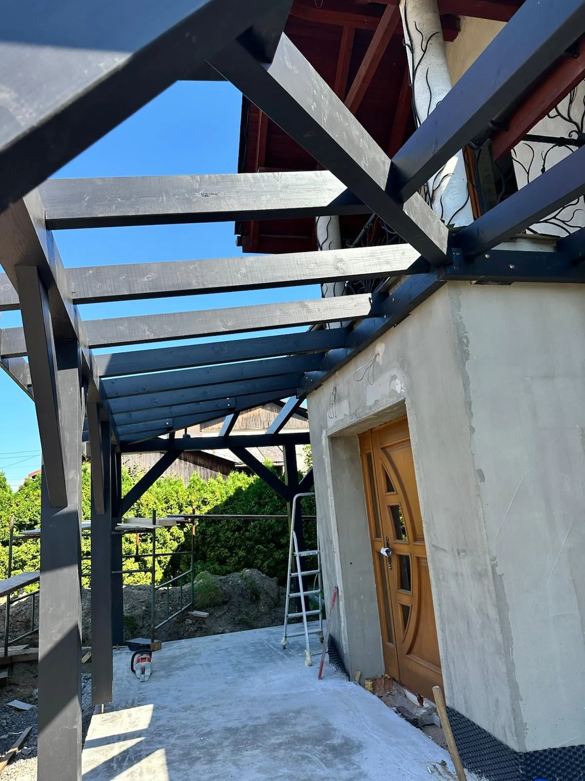 Detal konstrukcji z widocznym układem belek nad wejściem i starannie opracowanym wykończeniem.