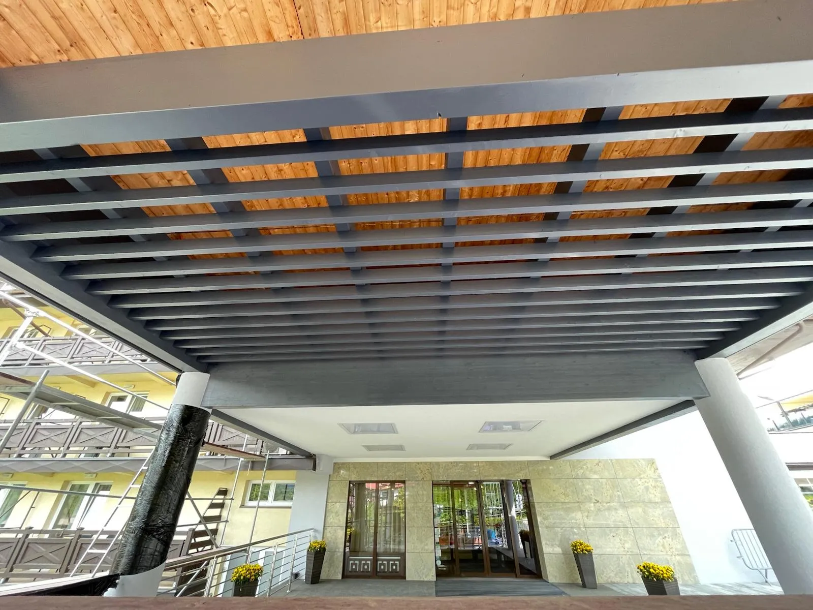 Spód gotowego zadaszenia z regularnym układem belek i estetycznie wykończonym poszyciem.