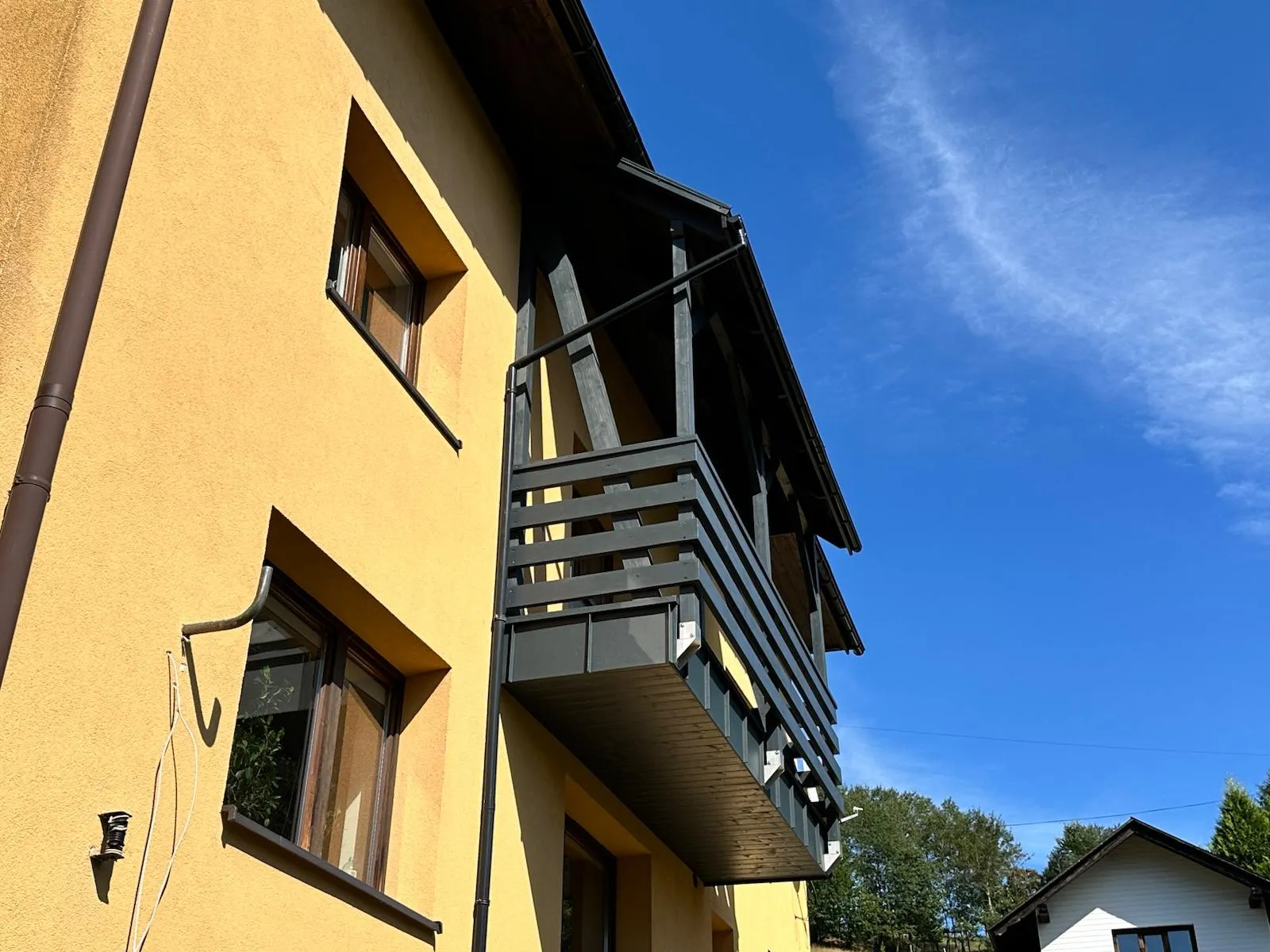 Boczny widok domu pokazujący, jak balkon z zadaszeniem porządkuje całą elewację.