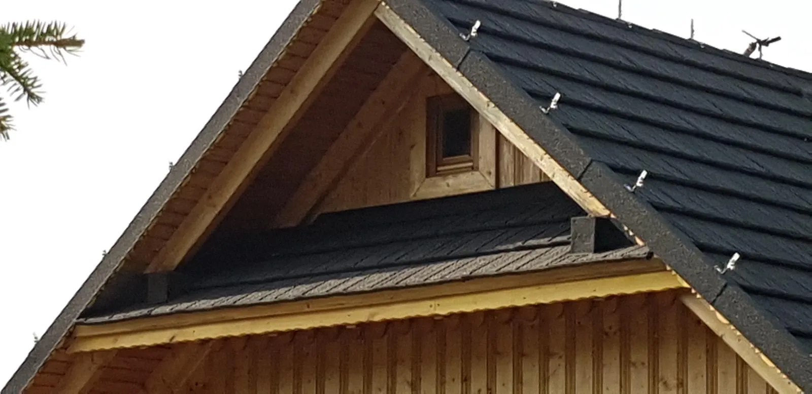 Szczyt budynku i warstwy pokrycia, które wymagały naprawy lub wymiany.