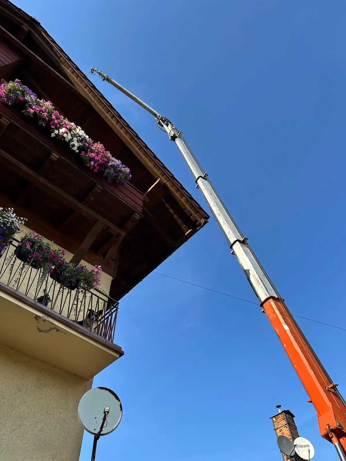 Professional mobile crane lifting large timber roof structure during heavy industry construction