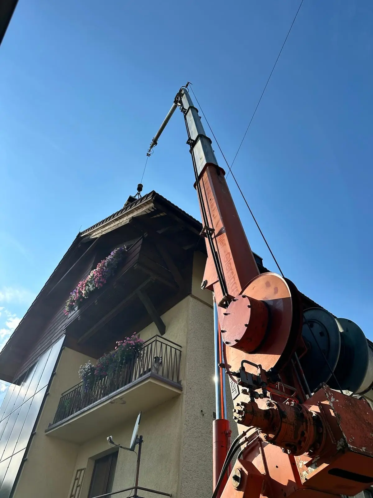 Modern construction site with a large yellow mobile crane lifting a massive timber beam against a clear sky